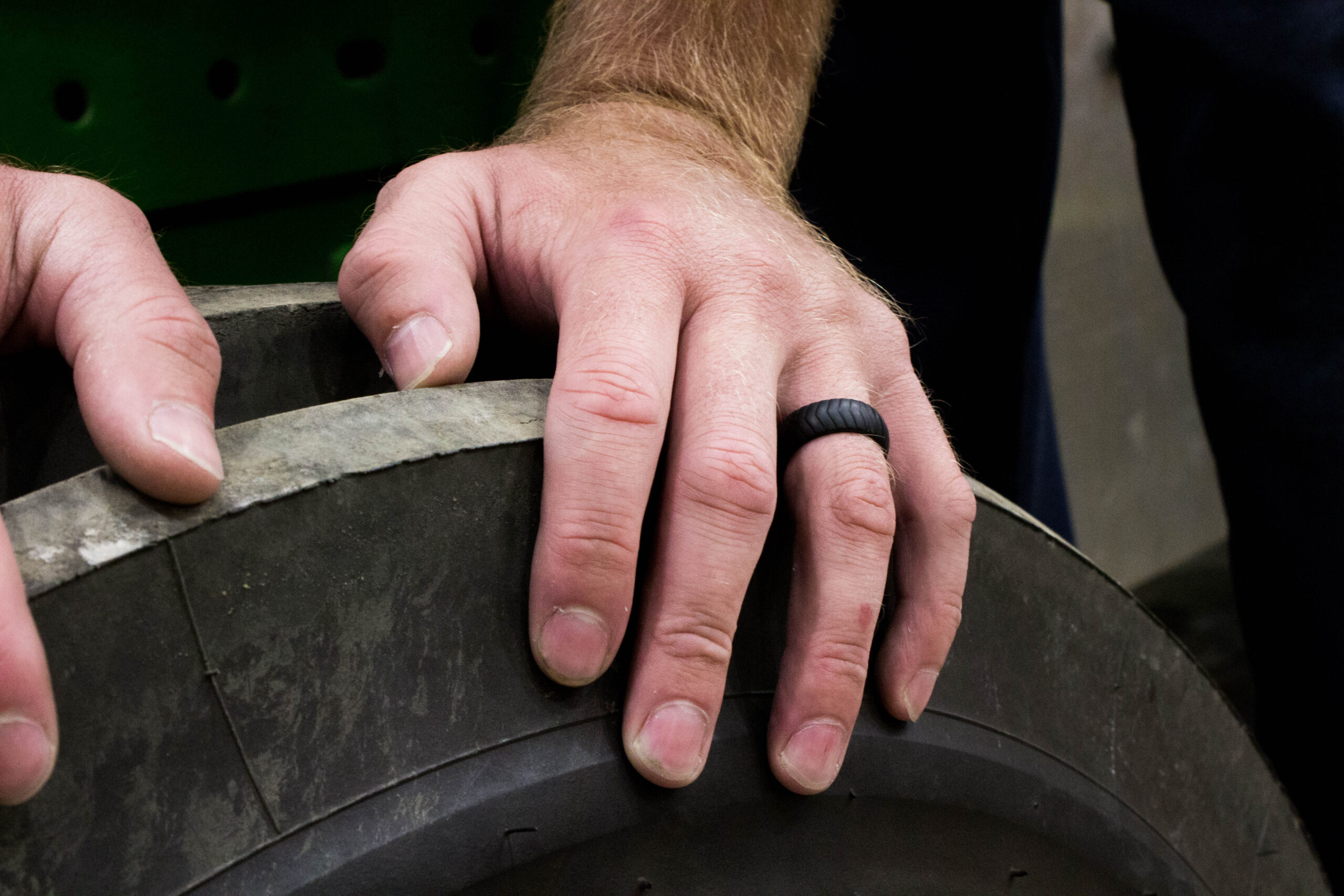 Man's hand on large tire, wearing silicone ring.